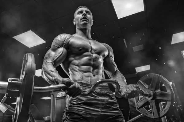 Bodybuilder träna med bumbbells vikter på gymmet — Stockfoto