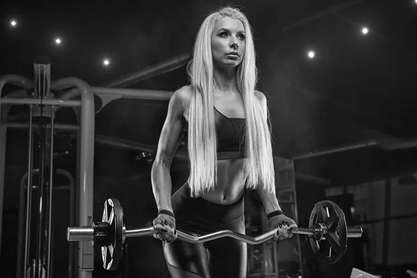 Joven hermosa chica atleta culturista en el gimnasio haciendo exerci — Foto de Stock