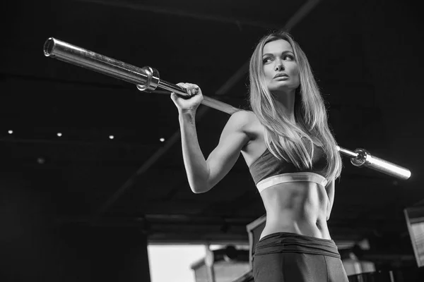 La chica en el gimnasio se agacha con una barra, en un hermoso spor —  Fotos de Stock