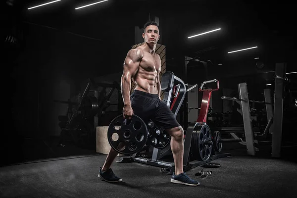 Ein junger männlicher Bodybuilder macht Übungen mit Sportgeräten, m — Stockfoto