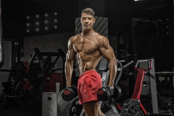 Bodybuilder che lavora con i pesi dei campanelli in palestra — Foto Stock