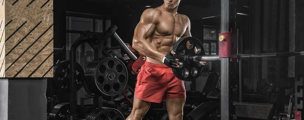 Culturista adulto joven haciendo levantamiento de pesas en el gimnasio. — Foto de Stock