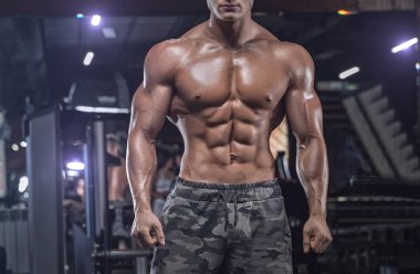 Spor salonunda ağırlık kaldıran genç bir vücut geliştirici..