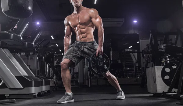 Hombre guapo haciendo ejercicios en el gimnasio sobre un fondo oscuro, nosotros — Foto de Stock