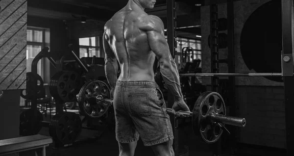 Hombre guapo haciendo ejercicios en el gimnasio sobre un fondo oscuro, nosotros — Foto de Stock