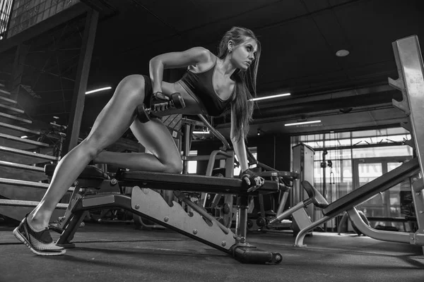 Fitness meisje met halters op een donkere achtergrond — Stockfoto