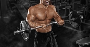 handsome man with big muscles trains in the gym, exercises for t clipart