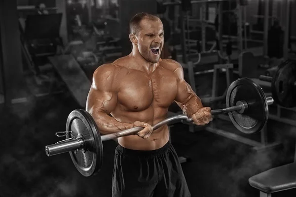 Schöner Mann mit großen Muskeln trainiert in der Turnhalle, Übungen für T — Stockfoto