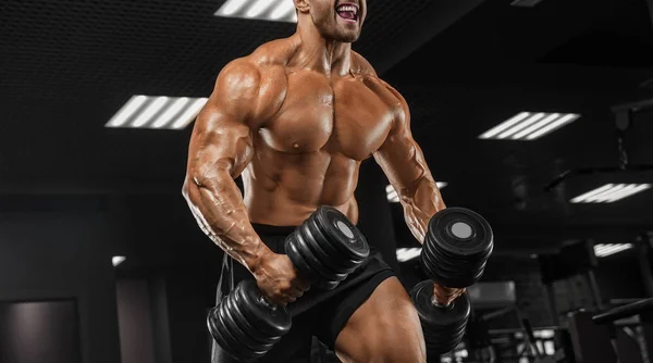 Schöner Mann mit großen Muskeln trainiert in der Turnhalle, Übungen für T — Stockfoto