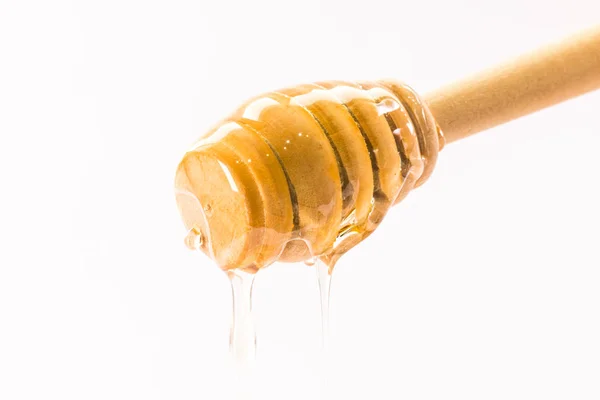 Miel goteando de un tarro de miel de madera aislado en blanco —  Fotos de Stock