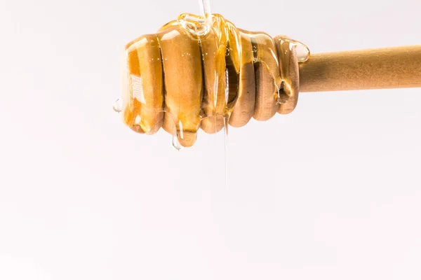 Miel goteando de un tarro de miel de madera aislado en blanco —  Fotos de Stock
