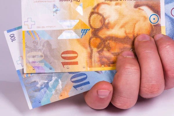 Een man houdt in zijn hand een close-up van de Zwitserse bankbiljet Stockfoto