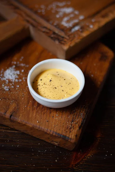 Closeup cheese sauce on wooden cutting board. — Stock Photo, Image