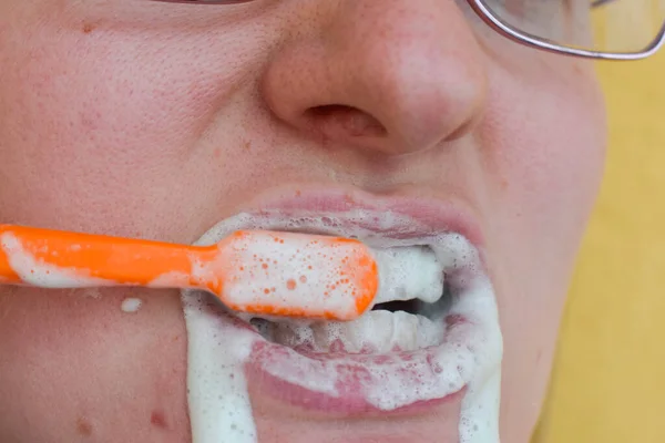 Girl brushing her teeth, lots of foam, close-up