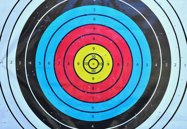 Archery target close up with many arrow holes in gold red blue a