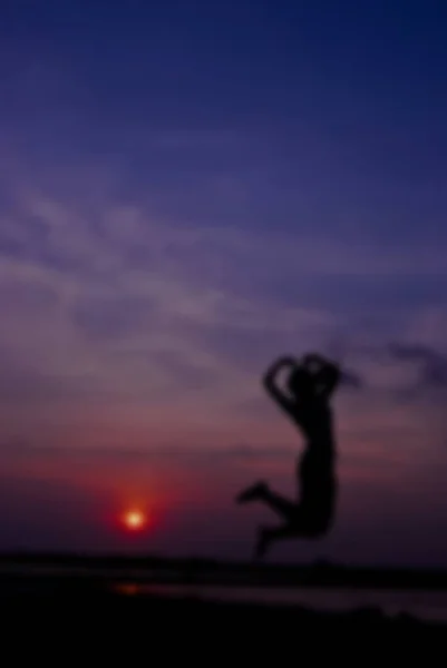 Sziluettjét boldog nő ellen ugrás gyönyörű naplementében. Ingyenes — Stock Fotó