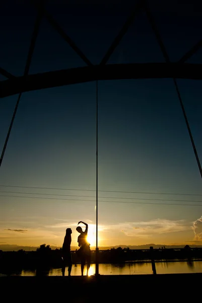 Couple in love silhouette holding hands heart-shaped on bridge — Stock Photo, Image