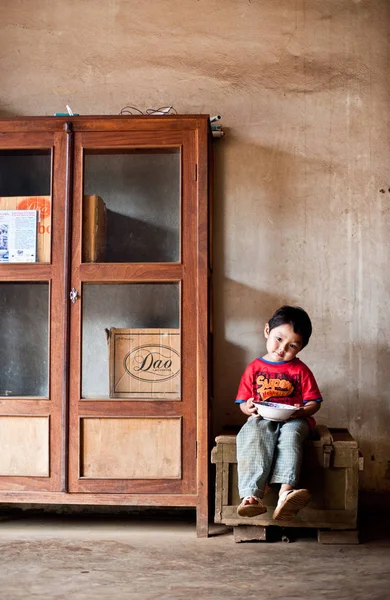 En oidentifierad Laos liten pojke sitter och äter i huset Pakse, Laos — Stockfoto