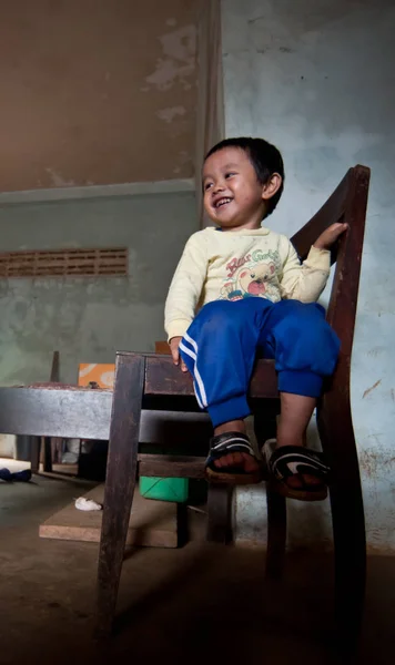 An unidentified Laos little boy sitting eating in the house of PAKSE, LAOS — Stock Photo, Image