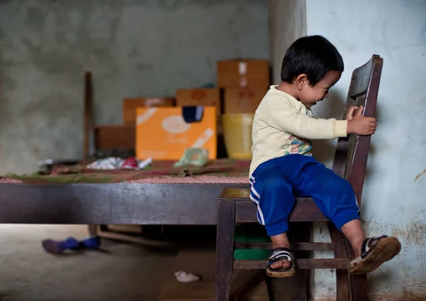 Неопознанный мальчик из Лаоса, сидящий в доме Паксе, штат Лаос — стоковое фото
