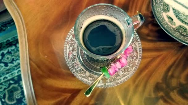 La mousse de café tourbillonne dans une tasse en verre avec du café. fond en bois . — Video