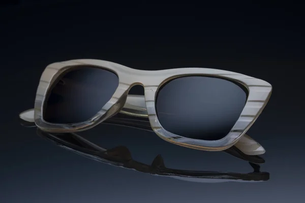 Женские солнцезащитные очки в пластиковой рамке на темном фоне с отражением — стоковое фото