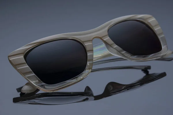 Sonnenbrille für Frauen im Kunststoffrahmen auf dunklem Hintergrund mit Spiegelung Stockbild