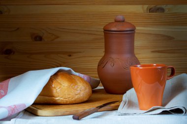 Tahta arka planda süt bardağı ve ekmek sürahisi.