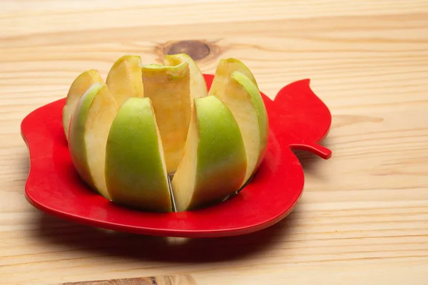 Apple kısmen Apple 'ın tahta arka planında Apple kesici ile kısmen kesilmiş ve tahta bir arka planda Apple kesici var.