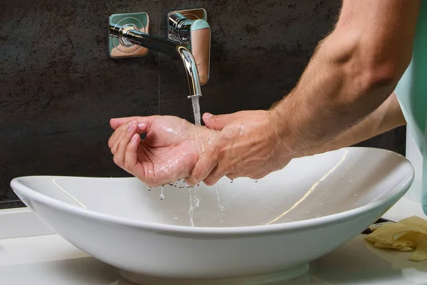 コロナウイルスのパンデミックを防ぐための防腐剤で水の下で人の手を洗うの写真を閉じるCovid — ストック写真