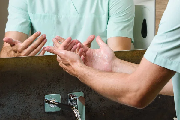 医者は水の下で洗浄した後 彼の手の清潔さを見て 病気のコロノウイルスを得ることを防ぐために防腐剤を使用してCovid — ストック写真