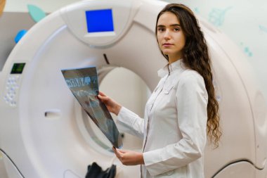 Tıp öğrencisi elinde hasta beyninin röntgen fotoğrafıyla kameraya bakar. Kadın KT komputer tomografinin önünde duruyor. Klinikteki genç kızın son kullanma tarihi geçmiş.