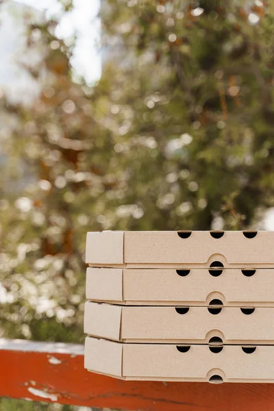 Promotion of 2+2 pizza boxes for food delivery. Isolated vertical photo of 4 cardboard pizza boxes with empty place in left side for text. Safery courier delivery from restaurant. Stop coronavirus