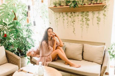 Uzun dalgalı saçlı genç kız kanepede oturuyor. Kadın gözlerini kapar ve bir erkeği düşler. Yeşil bahçede yaşam tarzı.