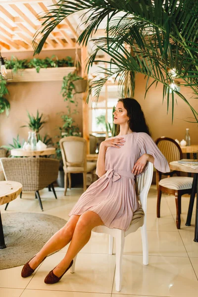 분홍색부드러운 여자가 의자에 왼쪽을 바라봅니다 커다란 카페의 — 스톡 사진