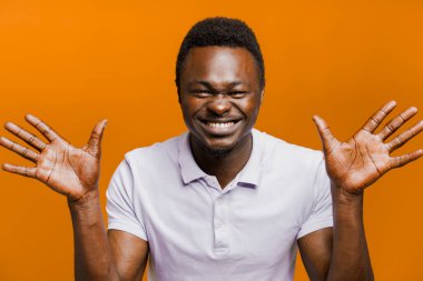 Komik siyah adam şakaları. Yakışıklı Afrikalı gülüyor ve ellerini kameraya gösteriyor. Koronavirüs karantinasında oyalanmak