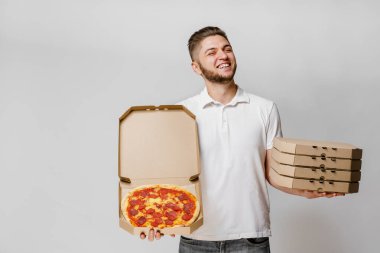 Pizzalı komik beyaz kurye ve pizzalı dört karton kutu. Yakışıklı adam pizza tutuyor ve gülümsüyor. Coronavirus karantina döneminde pizza teslimatı ilanı. Evde kal..