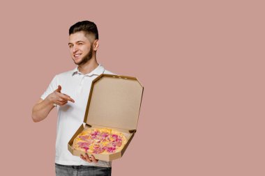 Pizzaya puan veren yakışıklı genç kurye. Metin reklamı için boş alan. Restorandan güvenli teslimat. Güvenilir öğrenci karantina döneminde kuryelik yapıyor. Hayatını kurtar ve evde kal..