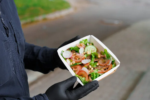 Green salad with veal and vagatables. Safety delivery with mask and black medical gloves at quarantine. Salad in eco thermo box. On line order from the restaurant delivered to people who stay at home.