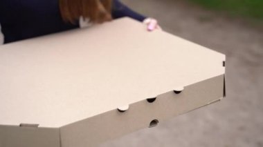 Kız büyük pizza kutusunu elinde tutuyor ve gidiyor. Yemeği götür. Bu çok büyük bir pizza. Karton eko kutusunda büyük boy pizza. Kurye büyük boy pizza alıyor. Evde kal.