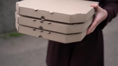 Kız kuryeden 3 pizza kutusu alıyor ve gülümsüyor. Pizzacıdan yemek servisi. 2 + 1 pizza teslimatı reklamı. Güvenli fast food teslimatı. Bir pizza bedava.. 