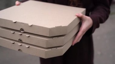 Kurye, genç kıza içinde pizza olan üç kutu verir. Pizzacıdan yemek servisi. 2 + 1 pizza teslimatı reklamı. Güvenli fast food teslimatı. Bir pizza bedava.. 
