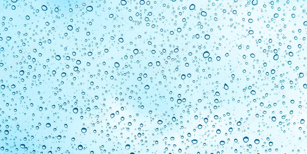 Blue water drops on glass or rain drop background 