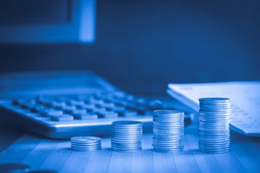 Hesap makineli para yığınları ve mavi filtreli hesap defteri arkaplanı