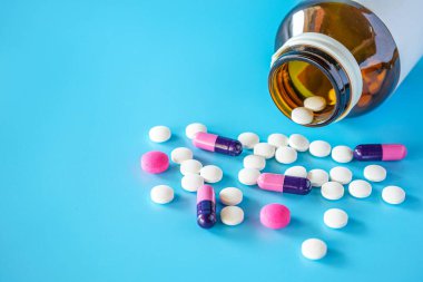 Teblets haplarını ve mavi arka planda seçici odaklı ilaç şişesini kapat