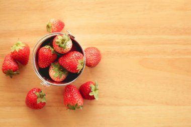 Küçük paslanmaz çelik kovadaki taze çilek manzarası ahşap masa üzerinde fotokopi alanı ile 