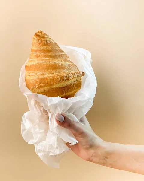 Croissant Fresco Una Mano Sobre Fondo Beige — Foto de Stock