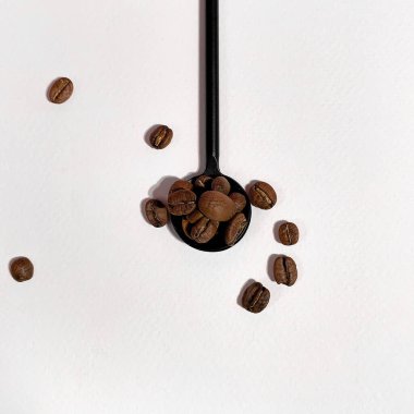 Beyaz arka planda siyah kaşık kahve taneciği 