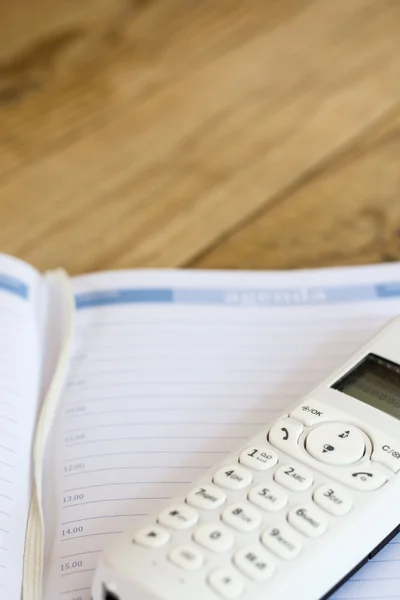 Phone and agenda business diary on the wooden table