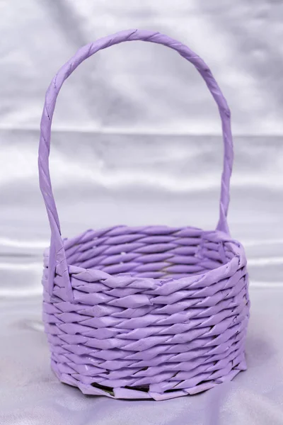 Purple flower arrangement woven basket over white satin